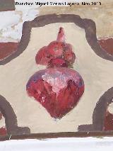 Capilla de Ntro Padre Jesús. Corazón en escudo del entablamento que tiene una policromía con corona de espinas y una llaga sangrante